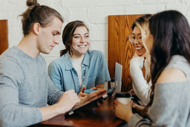 Cuatro compañeros alrededor de una mesa con una tableta y un portátil